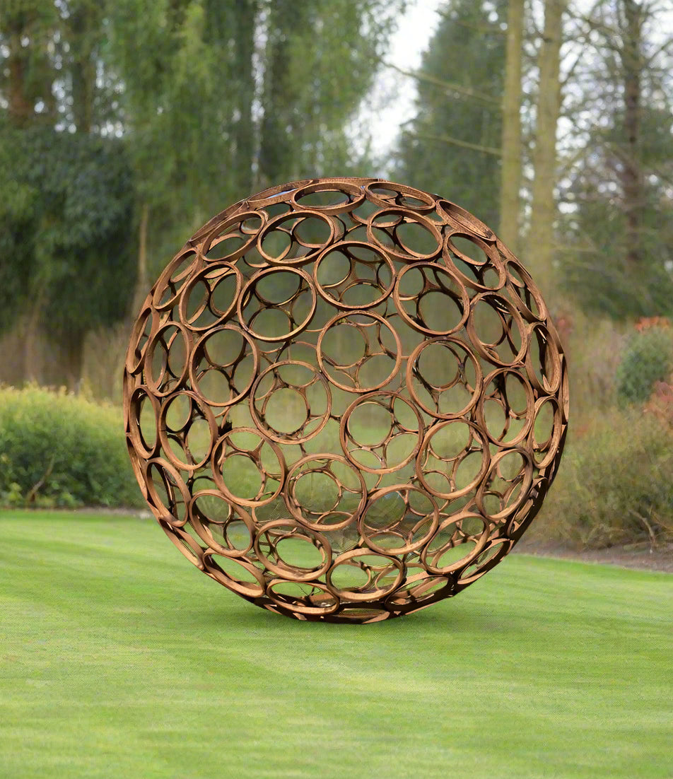 Large rustic garden sphere sculpture made of weathered steel rings, placed on grass, perfect for outdoor charm and geometric garden design.