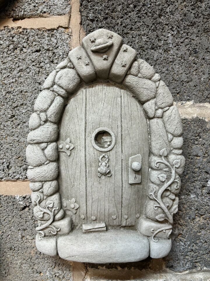 Stone Fairy Door Plaque with limestone finish, mounted on a wall. Features intricate floral and vine details, ideal for garden or tree decor.