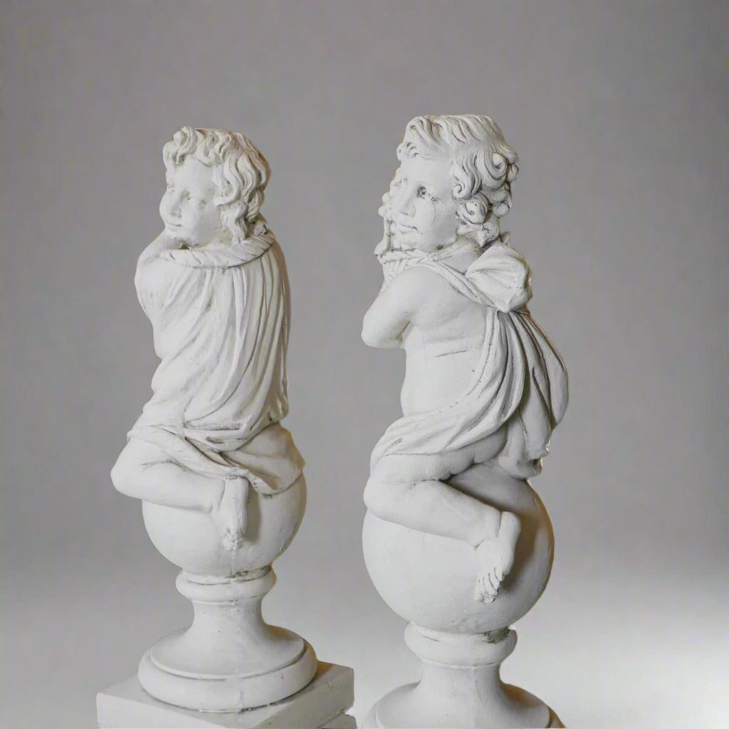 Rear view of hand-carved cherub statues from the Four Seasons collection, showing intricate drapery and craftsmanship in stone garden sculptures.