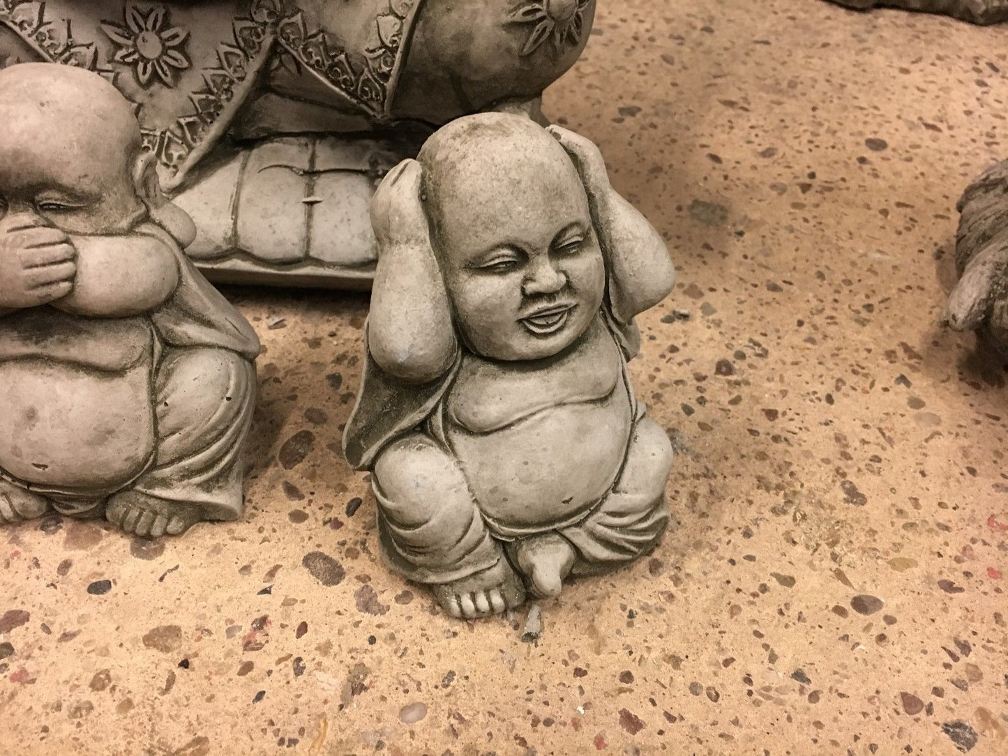 Detailed view of 'Hear No Evil' Buddha garden ornament with hands over ears, made from weather-resistant limestone.
