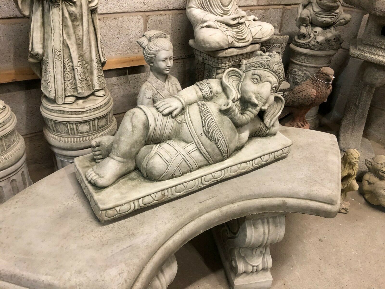 Stone Laying Down Ganesh Statue displayed on curved bench, perfect as a unique and weather-resistant garden ornament.