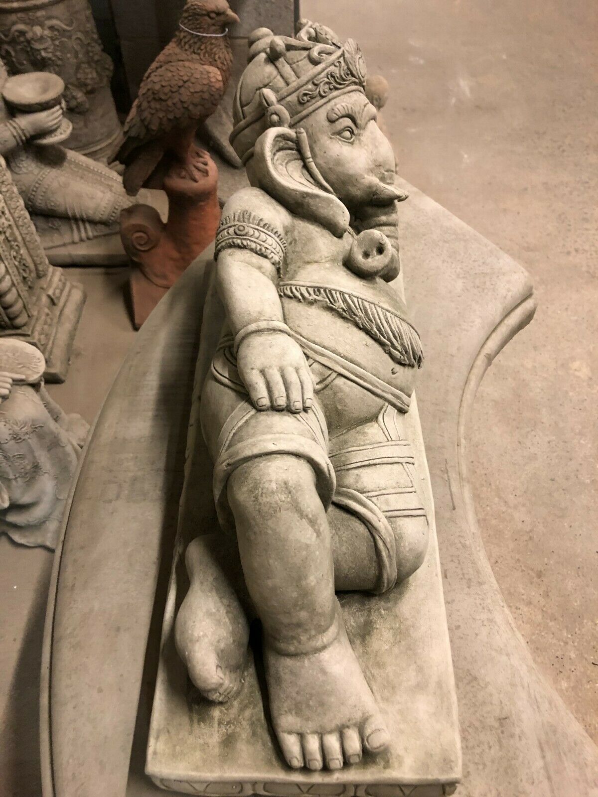 Top-down view of reclining Ganesh Statue made from limestone, showcasing detailed attire and robust design for outdoor use.