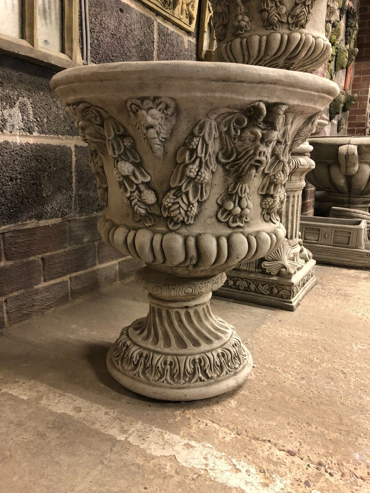 Detailed side view of Large Stone Bacchus Planter with mythological face carvings and fluted pedestal base, perfect for classic garden settings.