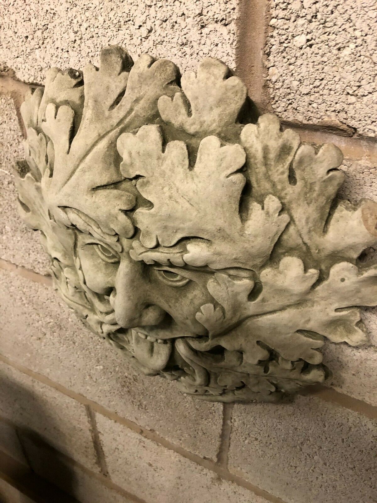 Angled shot of Stone Tongue Out Greenman Plaque showing expressive face and layered leaf design, perfect for hanging in home or garden settings.