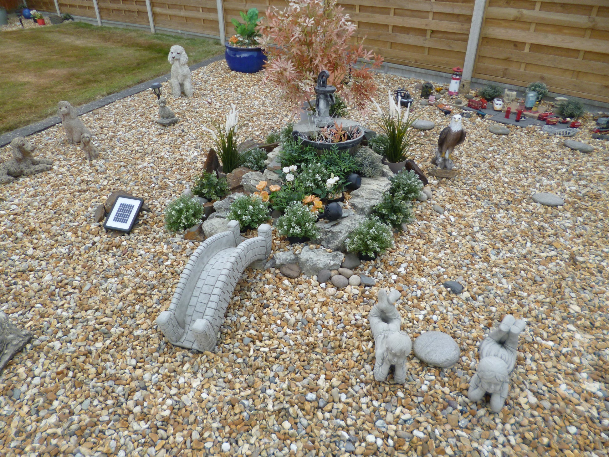 Stone pond bridge garden ornament with antique finish in a decorative rock garden, enhancing a central water feature with animal statues.