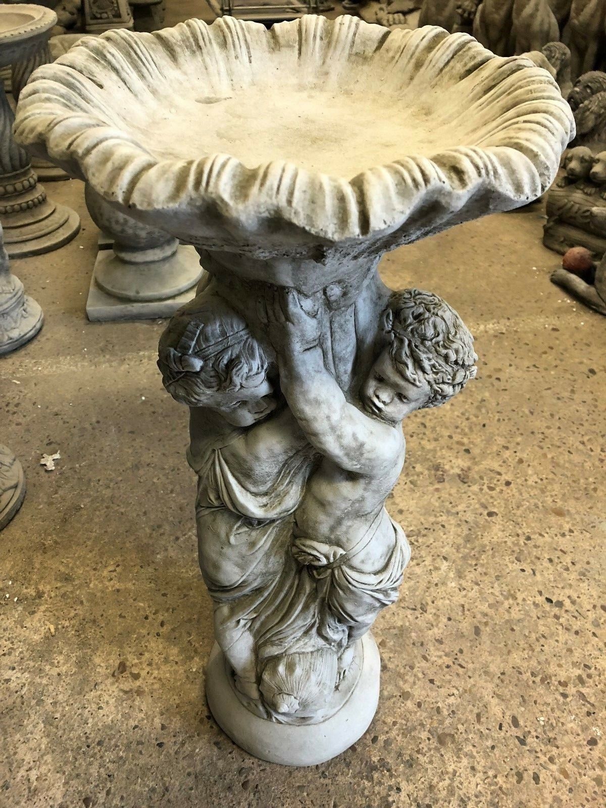 Stone Cherub Garden Bird Bath with antique grey finish, featuring two cherubs holding a scalloped basin. Ideal for outdoor garden decoration.