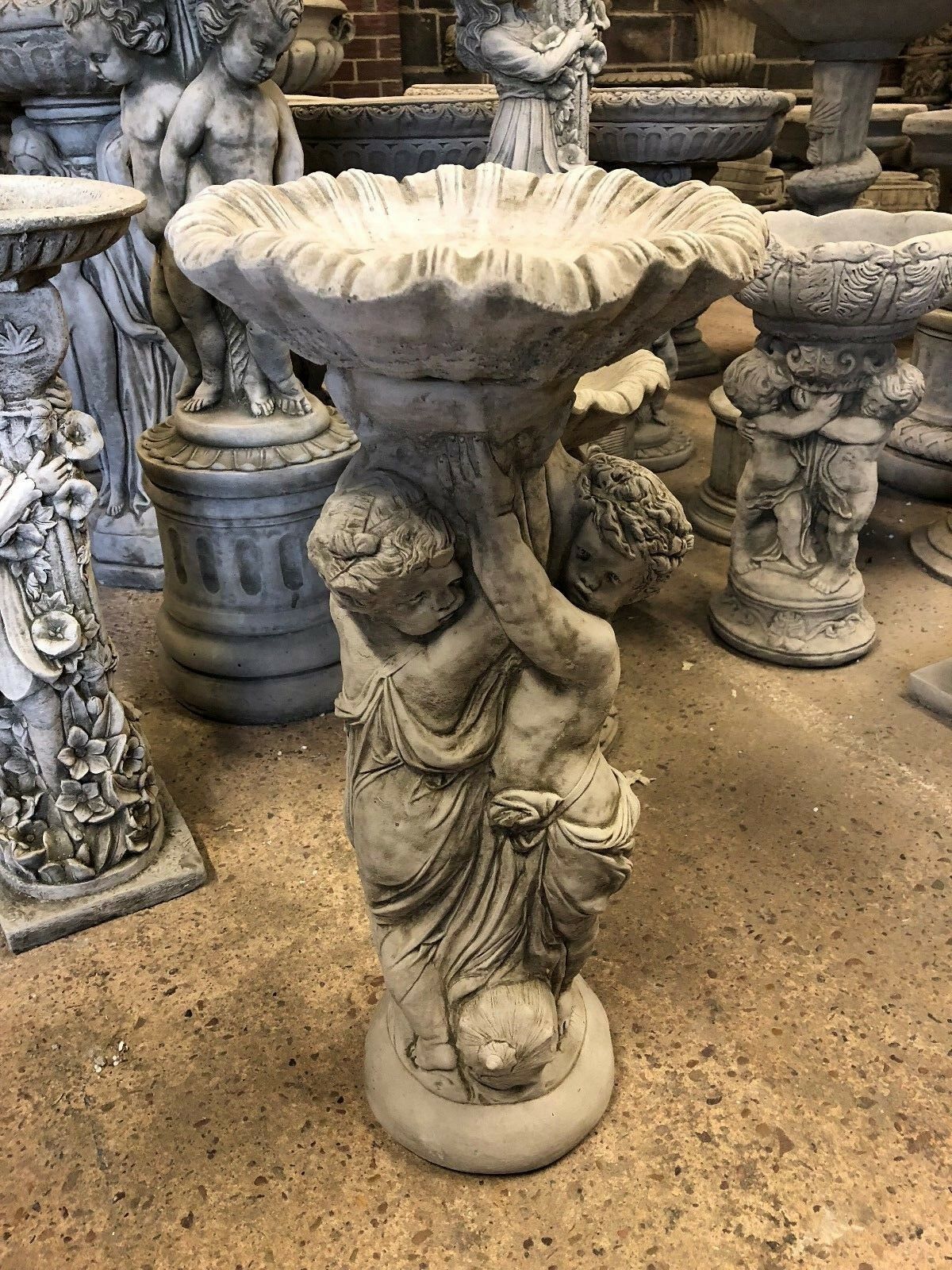 Heavy-duty Stone Cherub Garden Bird Bath in antique finish, showcasing detailed cherub figures and ornate basin design for garden or patio use.