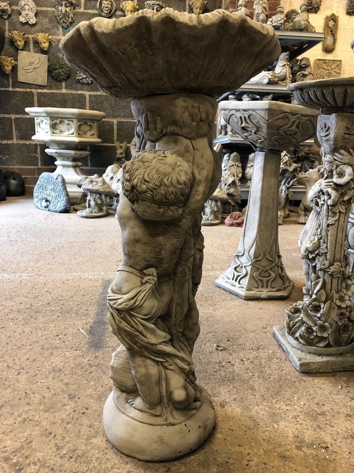 Side profile of Stone Cherub Garden Bird Bath, highlighting intricate cherub sculpture and durable limestone construction for outdoor settings.