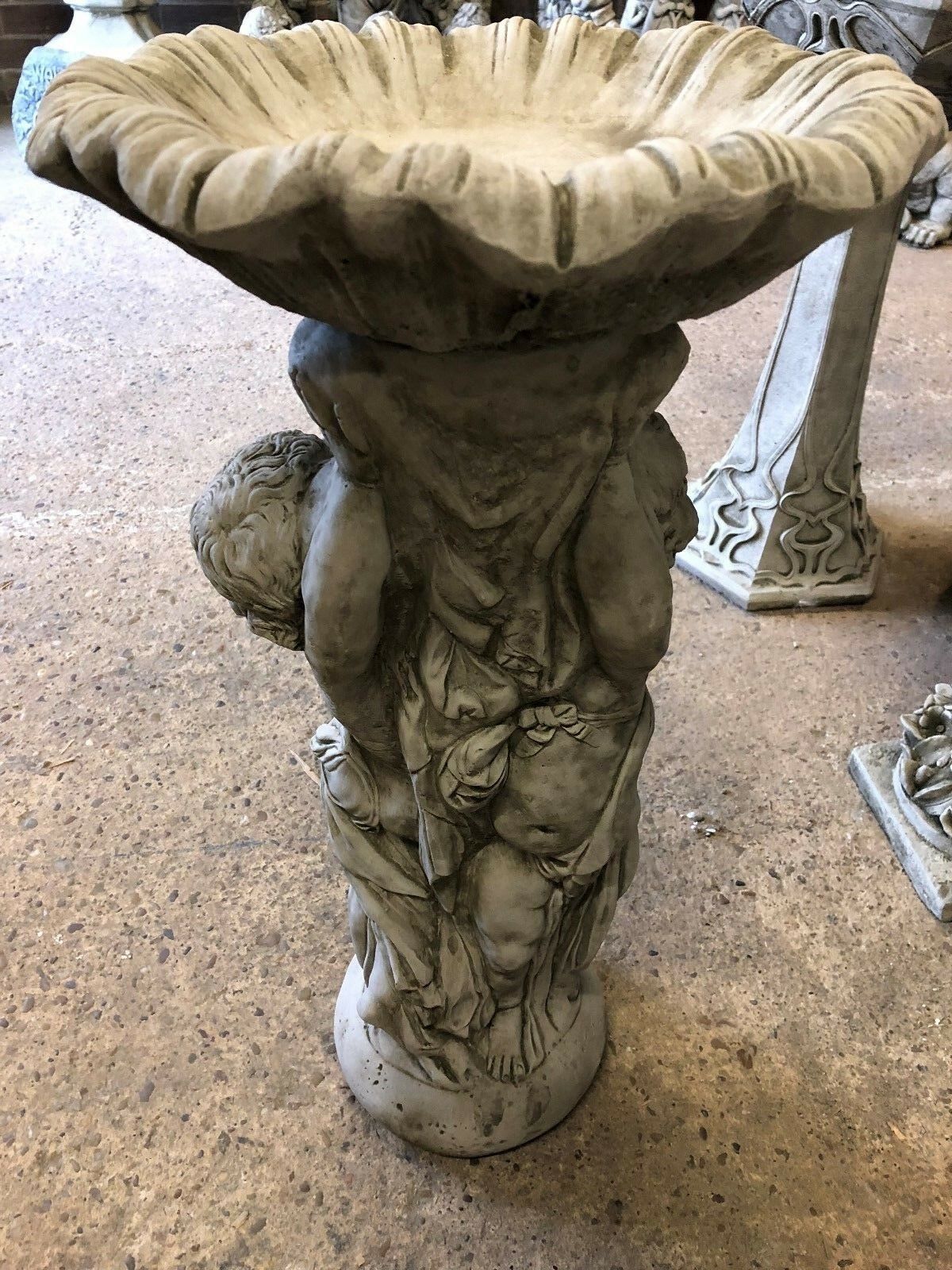 Rear view of Stone Cherub Garden Bird Bath in antique grey, showing detailed craftsmanship and solid stone base for stability in outdoor areas.