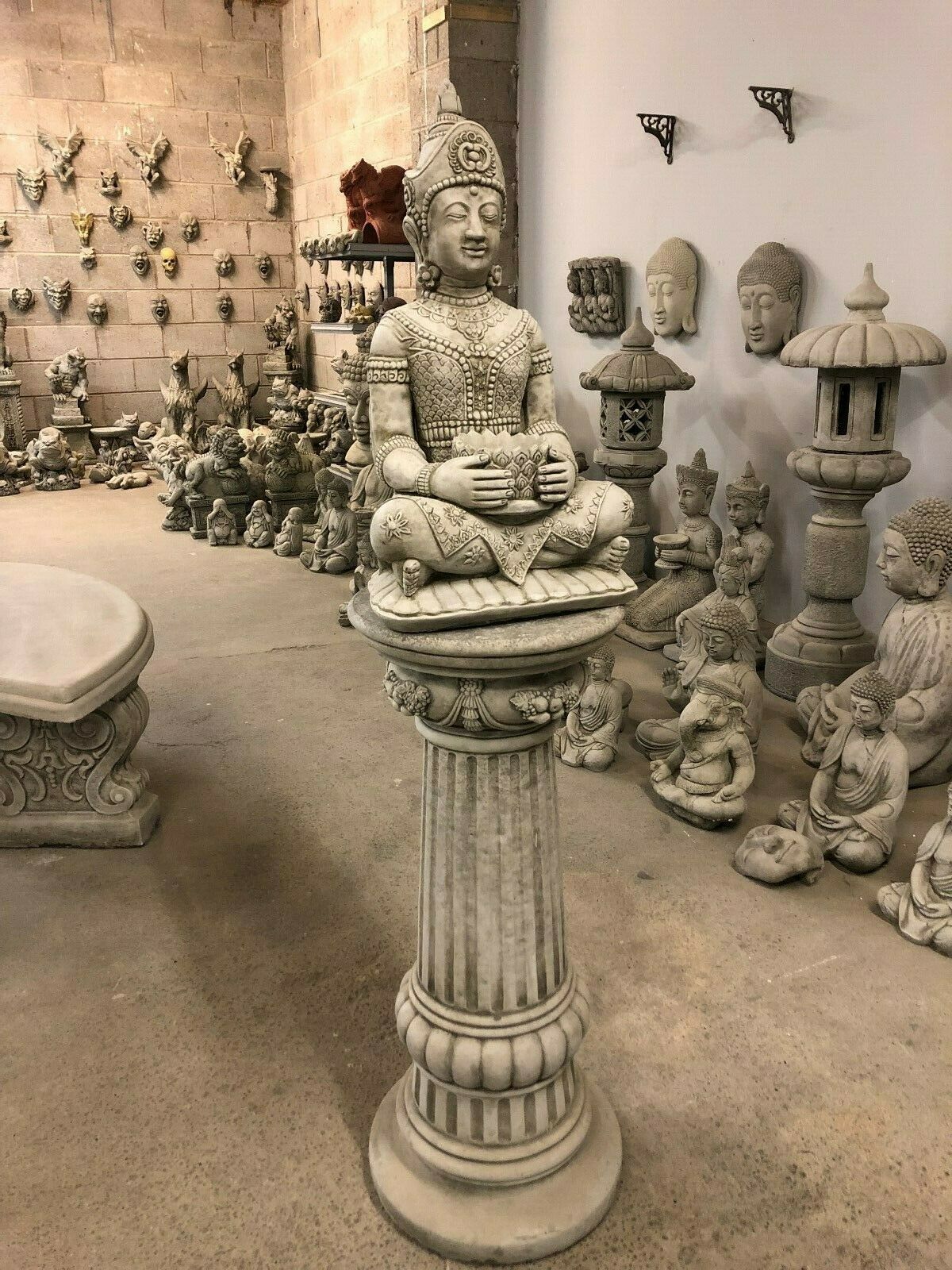 Stone Buddha Bust - Garden Ornament featuring a serene, intricately detailed Buddha seated on a tall fluted plinth. Ideal for tranquil outdoor decor.