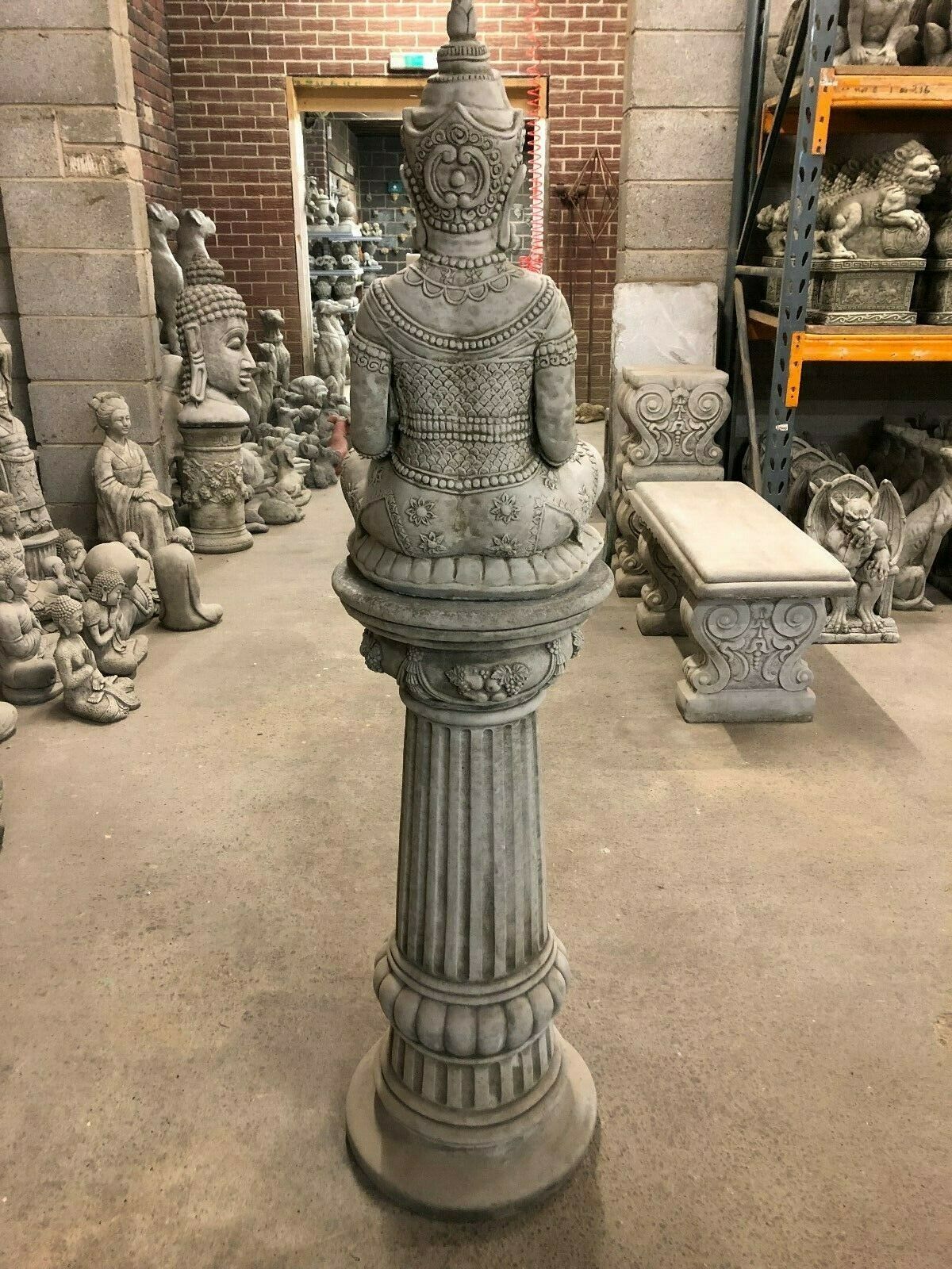 Back full-length view of Stone Buddha Bust - Garden Ornament on a fluted pedestal, perfect for enhancing peaceful garden aesthetics.
