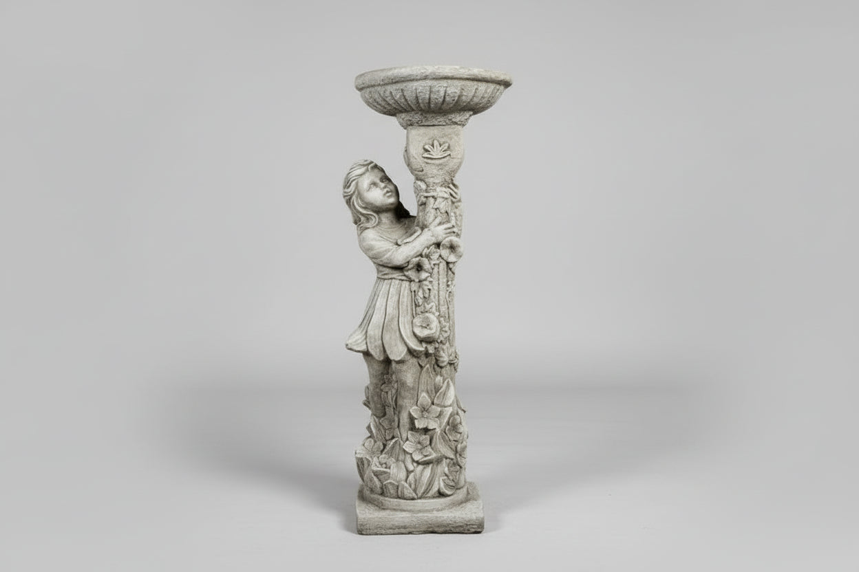 Decorative stone sculpture of a figure holding a bowl against a stone wall.